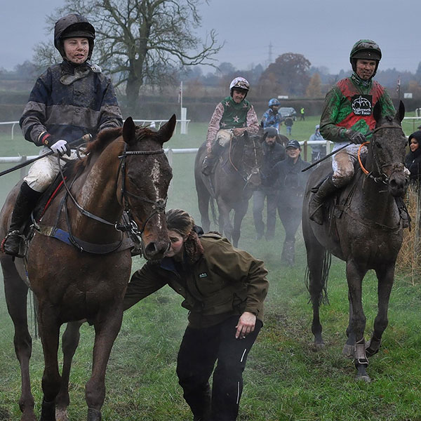 Jockeys carrying saddles